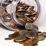 Jar of coins tips over with coins spilling out